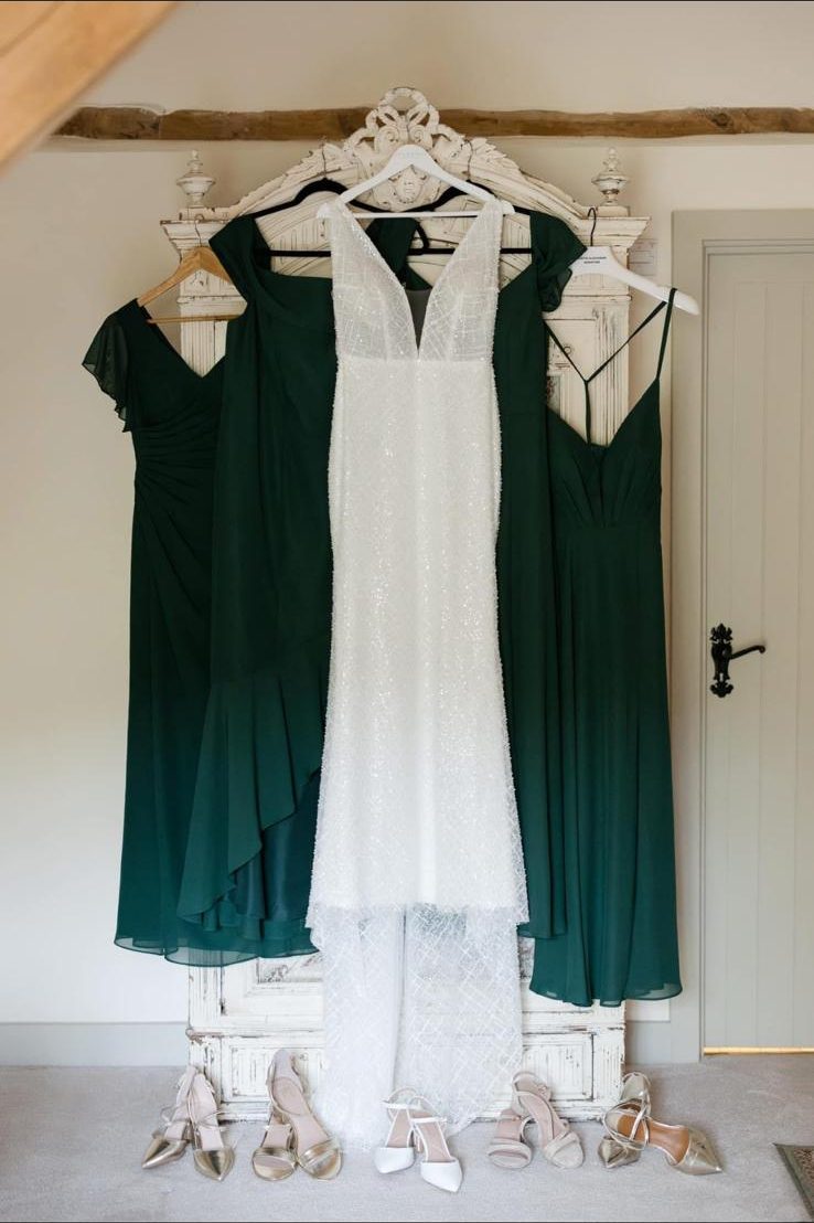 Green bridesmaid dresses either side of a white lace dress, freshly cleaned