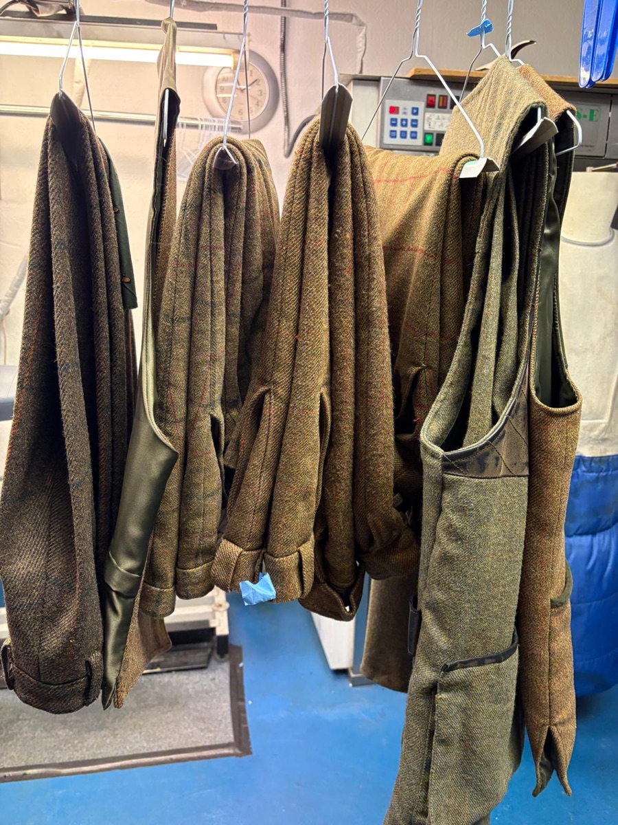 Tweed jackets and waistcoats hanging after cleaning at Tudor Dry Cleaners